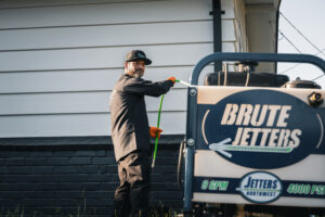 Technician operating hydro jetting equipment at residential home for drain cleaning service.