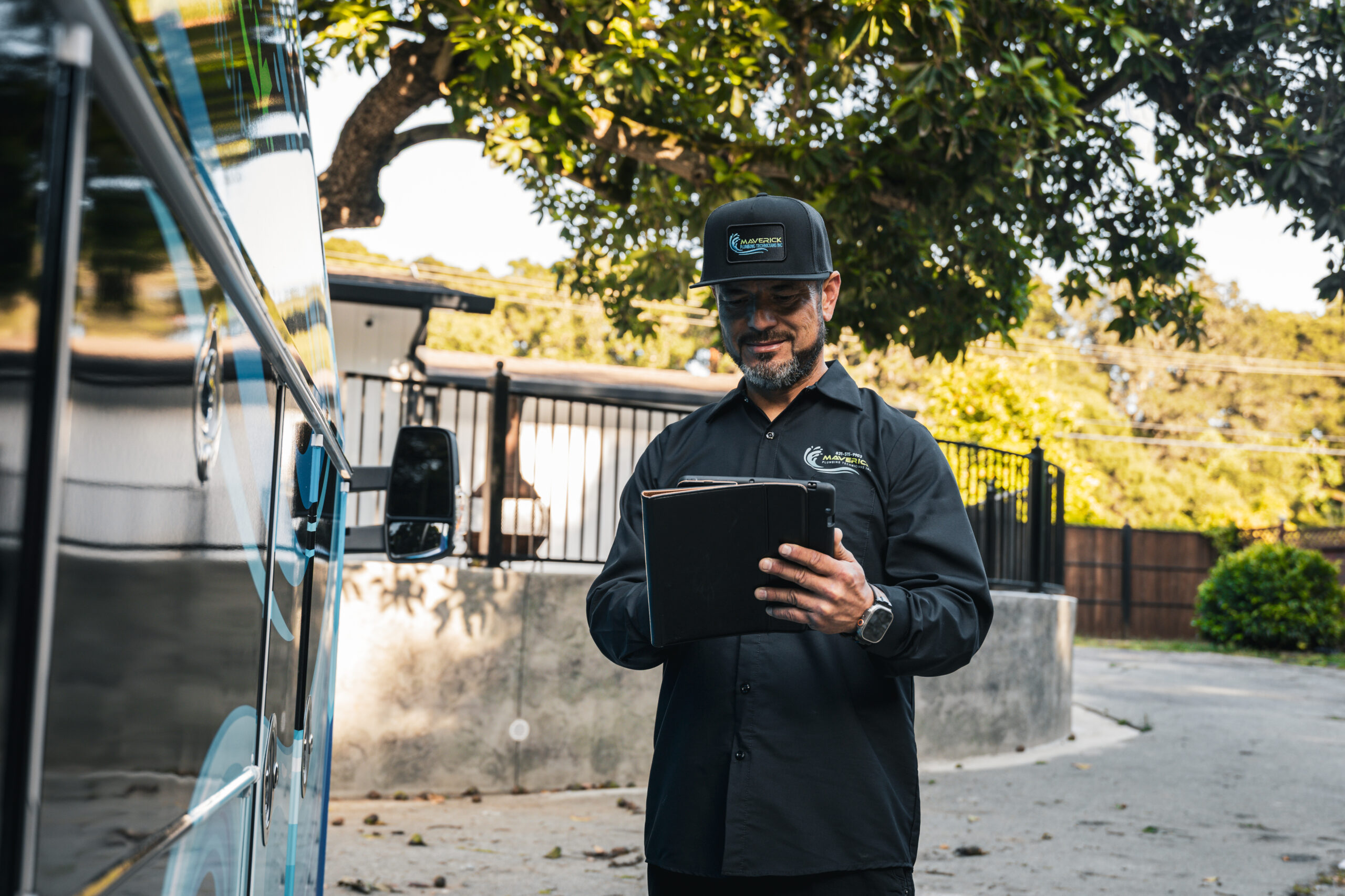 Maverick Plumbing technician with tablet next to service van, ready for service call